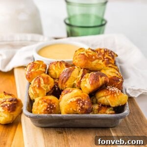 Easy Biscuit Pretzel Bites with Cheese Sauce on a tray sitting on table with a glass to the side