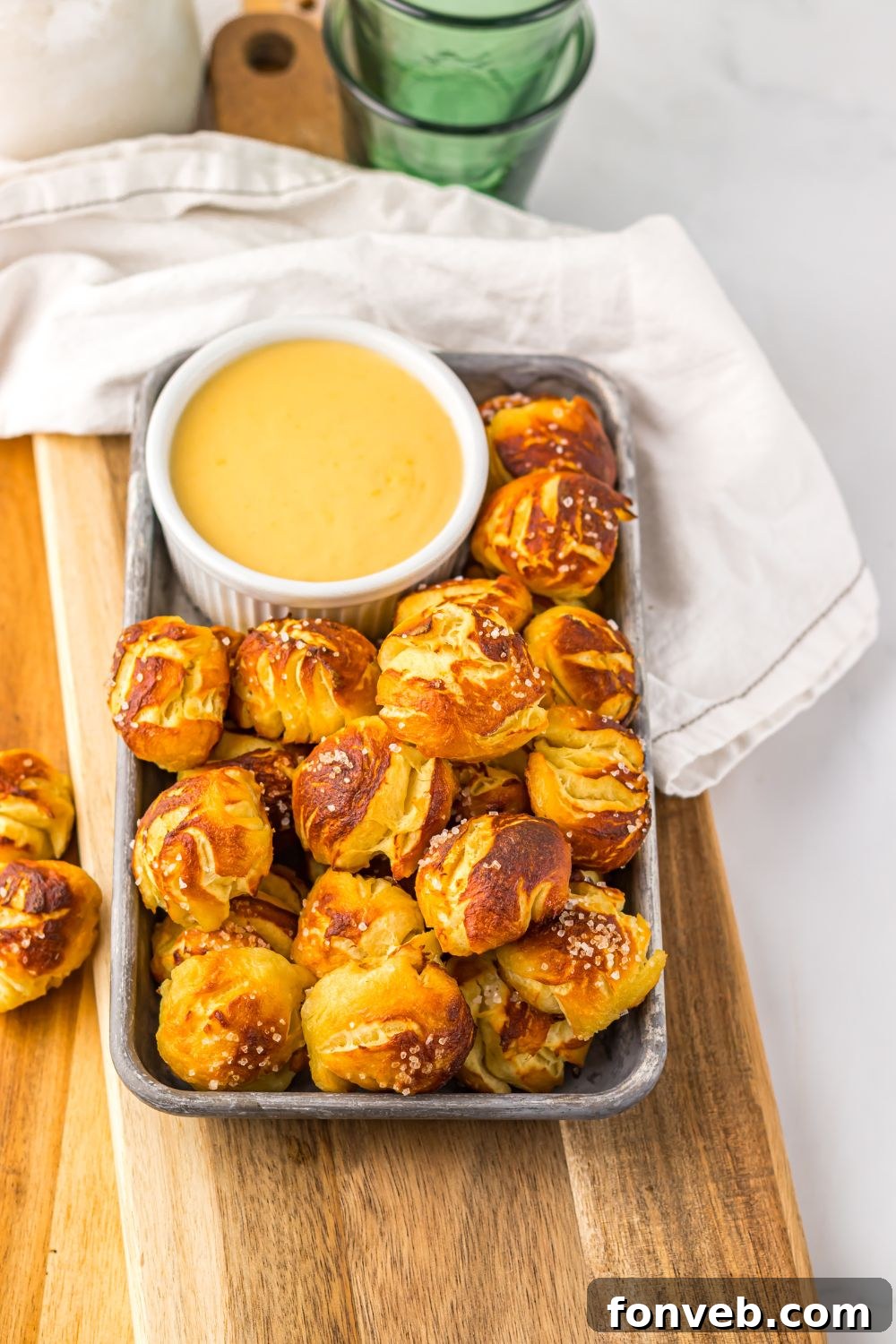 Easy Biscuit Pretzel Bites with Cheese Sauce on a tray sitting on table with a towel to side 