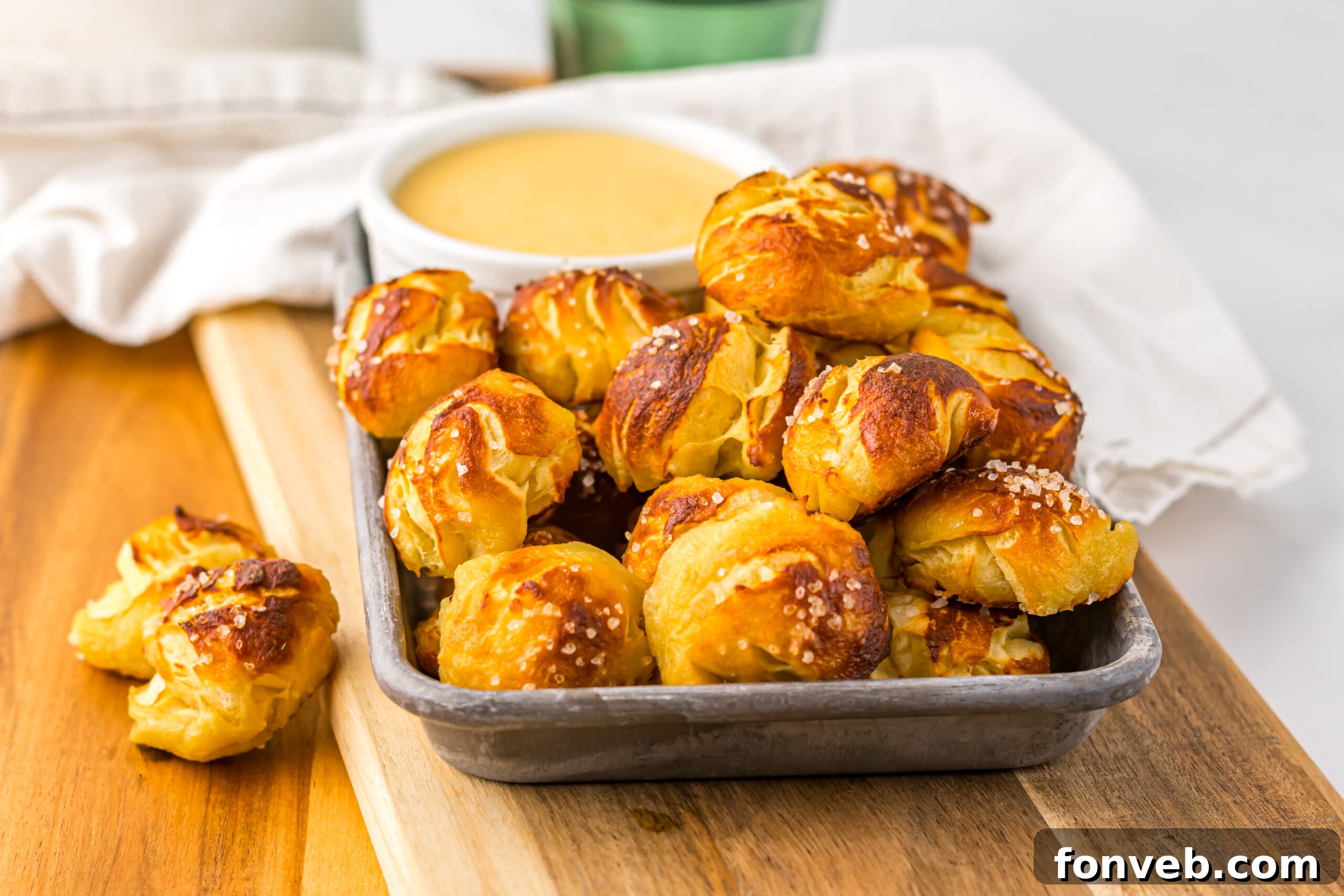 Easy Biscuit Pretzel Bites with Cheese Sauce on a tray sitting on a wooden table 