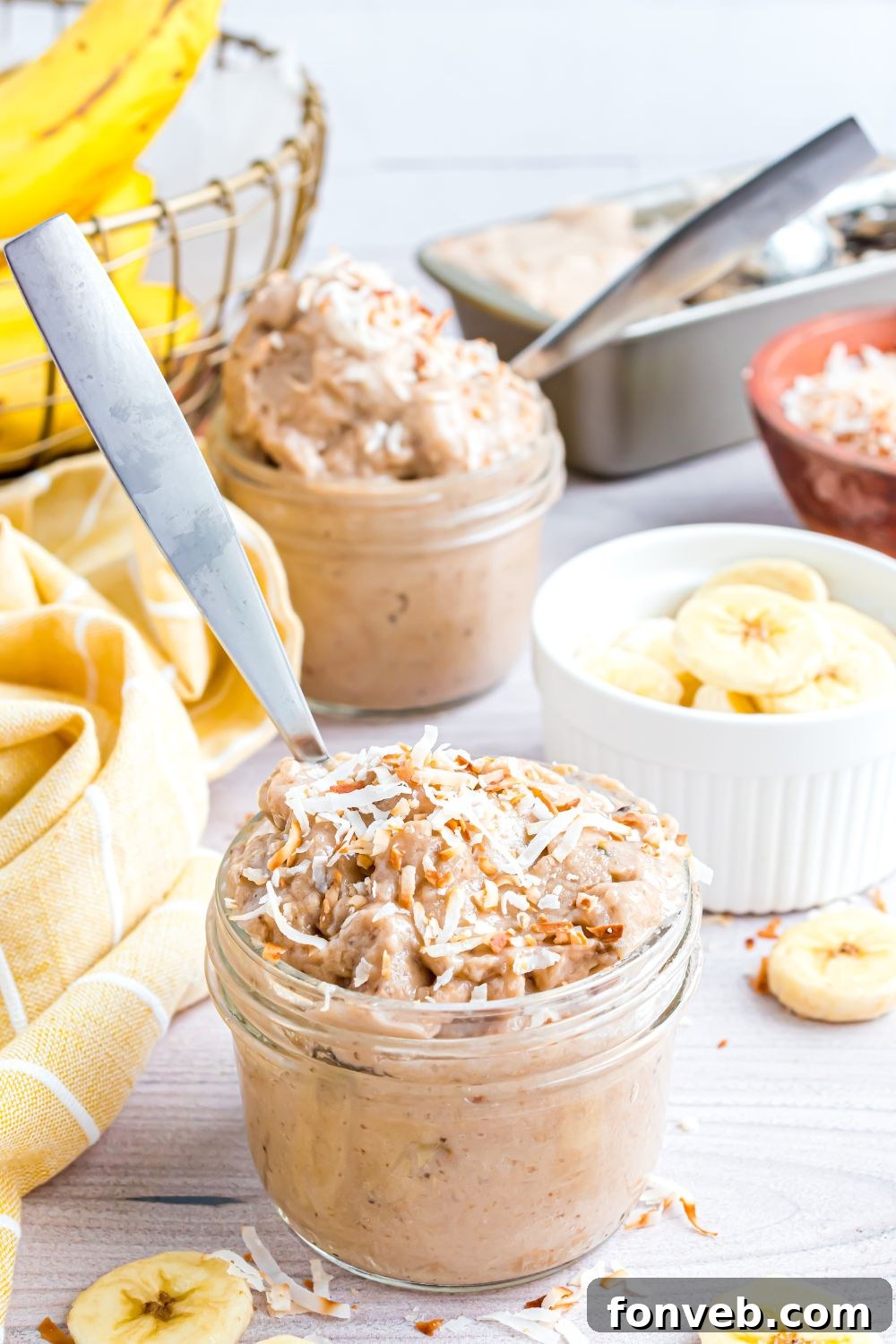 Banana Ice Cream: The One-Ingredient Wonder 15 Banana Ice Cream in bowls with toppings on top and spoons in bowls, and bananas sliced in a white bowl on table