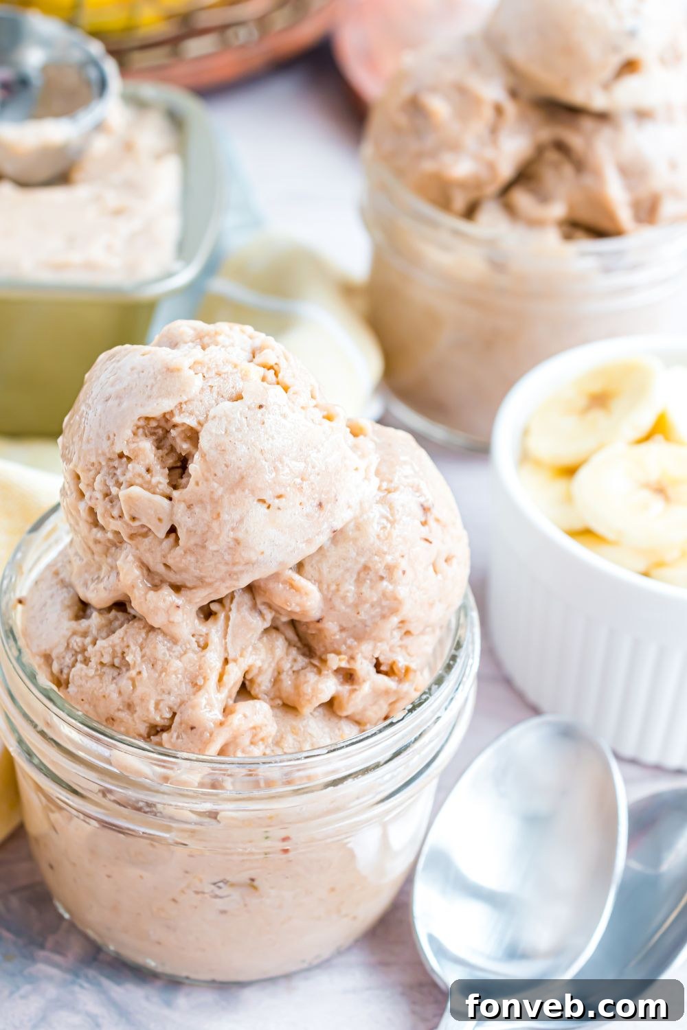 Banana Ice Cream: The One-Ingredient Wonder 18 Banana Ice Cream in a glass bowl with fresh sliced bananas to side and spoons on table