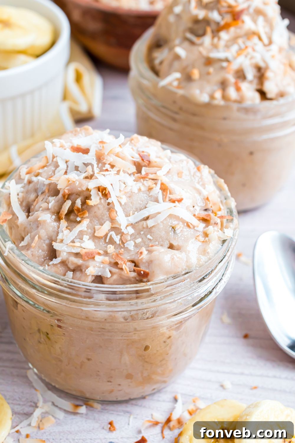 Banana Ice Cream: The One-Ingredient Wonder 22 Banana Ice Cream in bowl topped with toasted coconut, and spoons and nuts around table