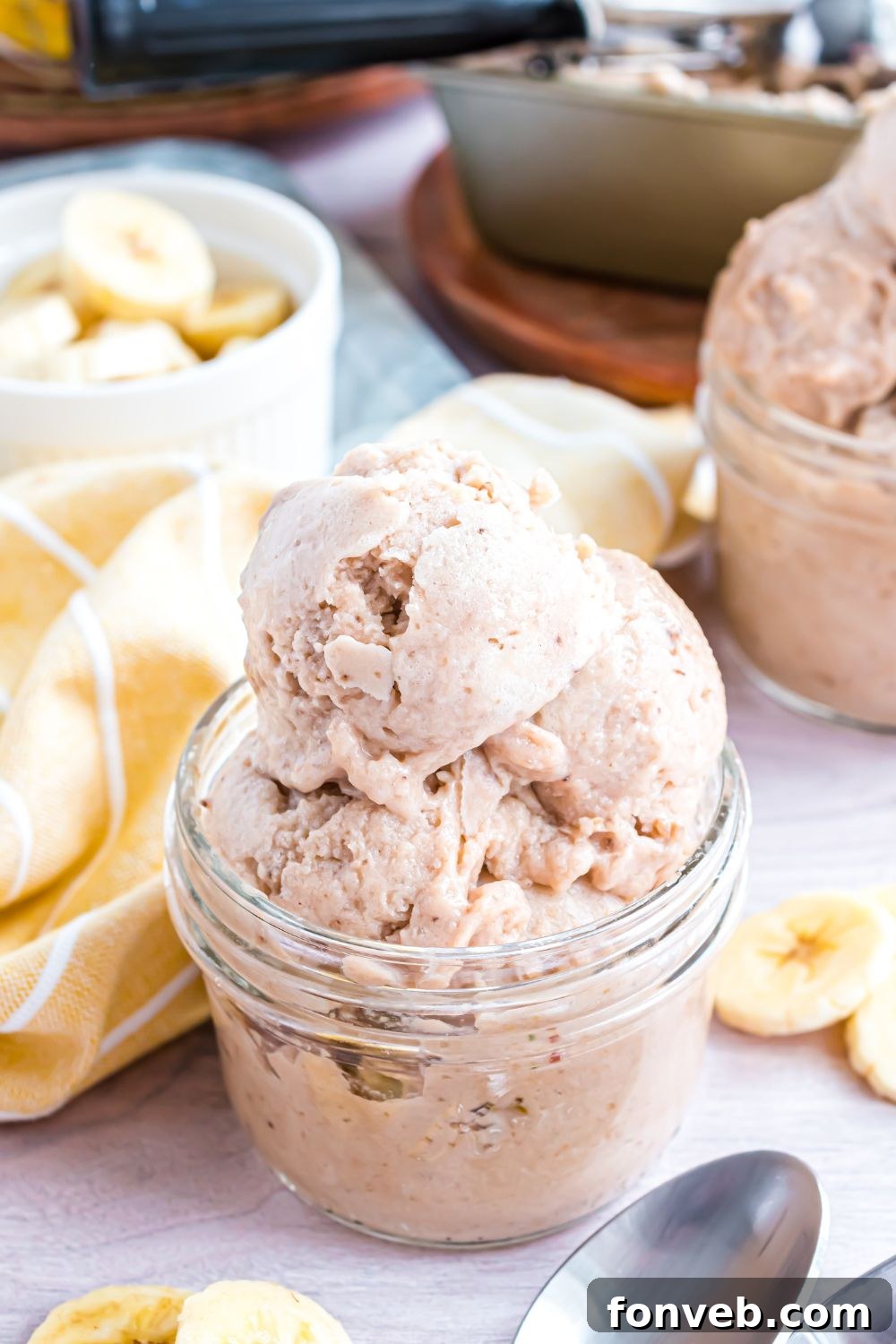 Banana Ice Cream: The One-Ingredient Wonder 24 Banana Ice Cream in jars with a yellow towel between bowls and sliced bananas in a bowl behind the ice cream