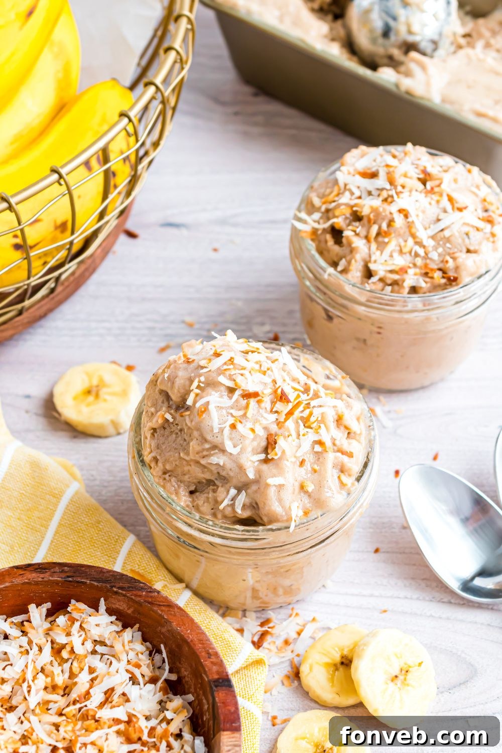 Banana Ice Cream: The One-Ingredient Wonder 4 Banana Ice Cream in glass bowls on table with a basket of bananas to side, and spoons and sliced bananas on table