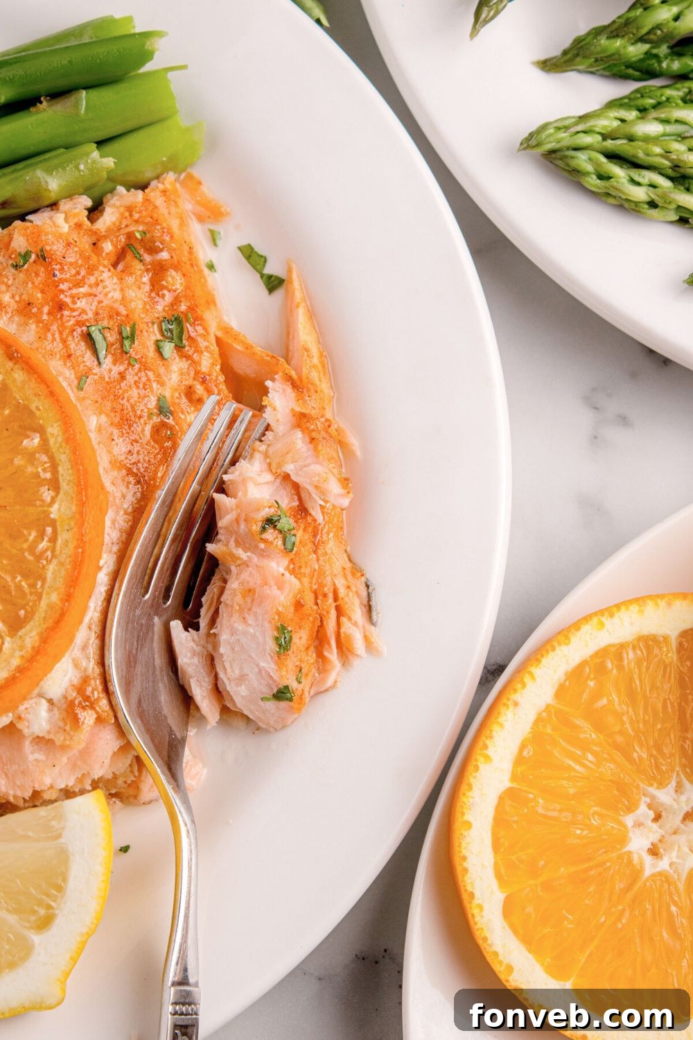 Effortless Honey Mustard Salmon Foil Grill 13 Grilled Honey Mustard Salmon on plate with a fork biting into a piece of it with asparagus on a second plate