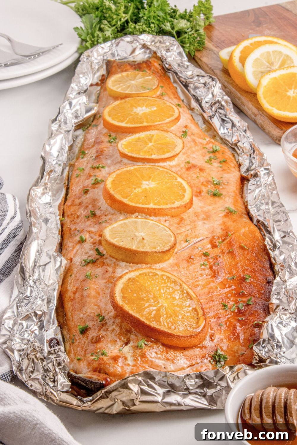 Effortless Honey Mustard Salmon Foil Grill 18 Grilled Honey Mustard Salmon in Foil on table with a bowl of honey to side, sliced oranges, and more around table
