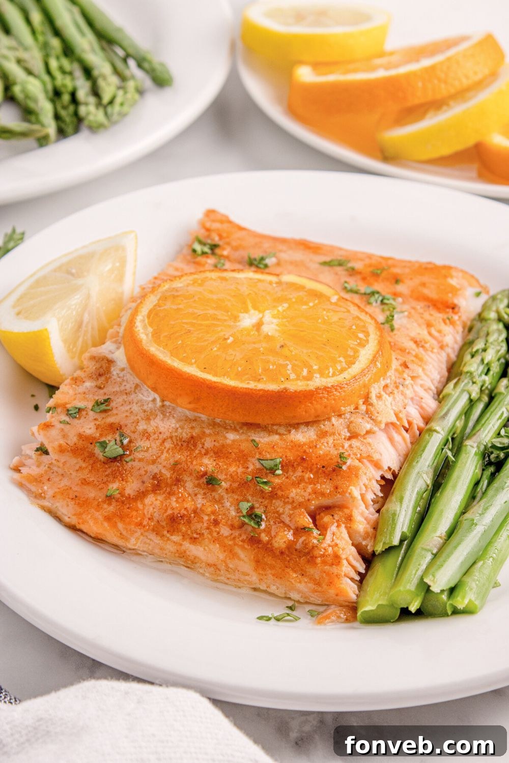 Effortless Honey Mustard Salmon Foil Grill 21 side view of table with a plate of Grilled Honey Mustard Salmon, a side of asparagus, and lemon wedge to side