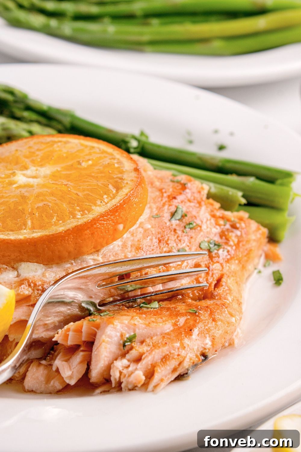 Effortless Honey Mustard Salmon Foil Grill 23 Grilled Honey Mustard Salmon on plate with a fork cutting into salmon with asparagus tose side and on a second plate