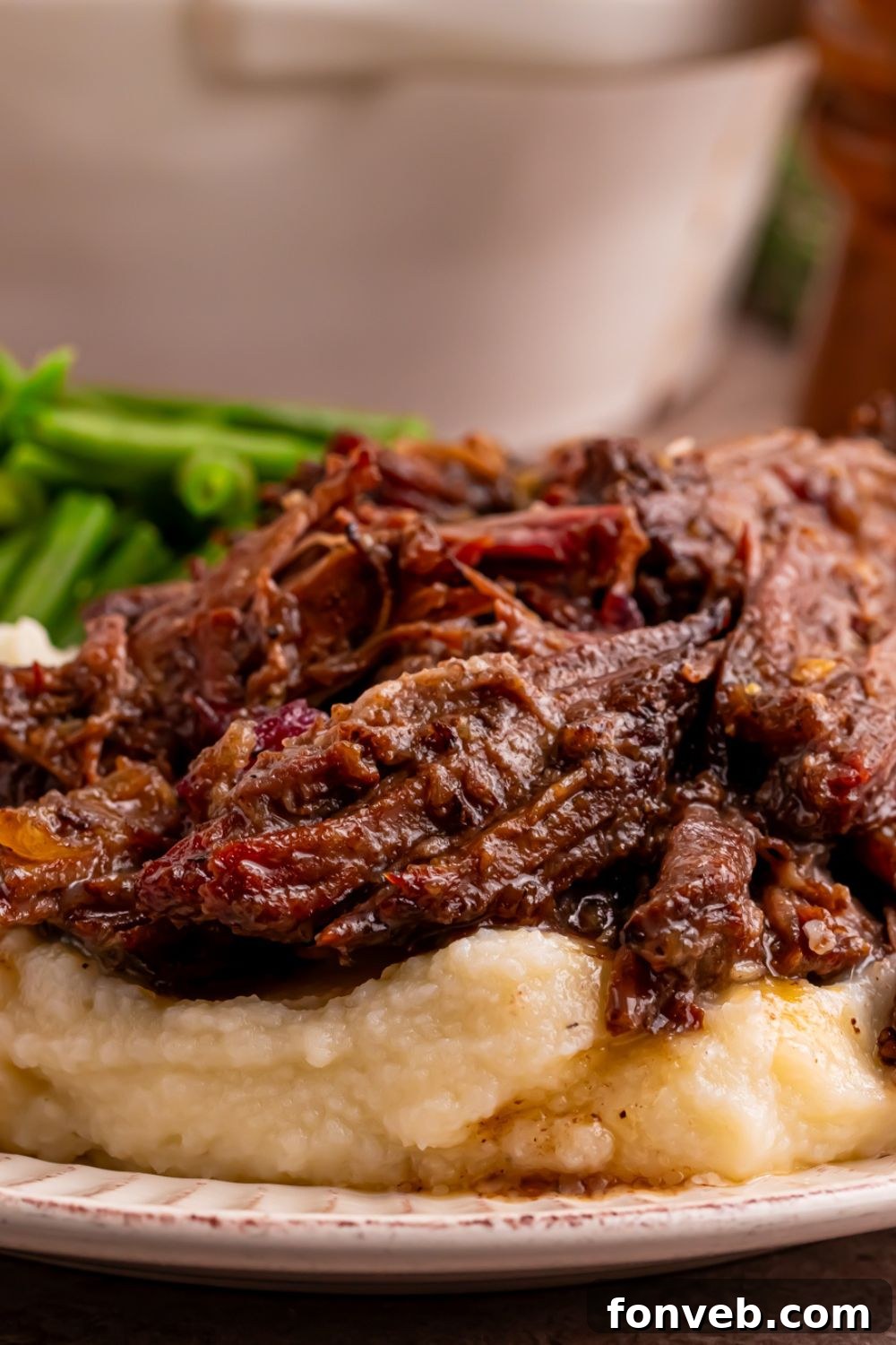 Cranberry Pot Roast on plate with mashed potatoes under it and a side of green beans 