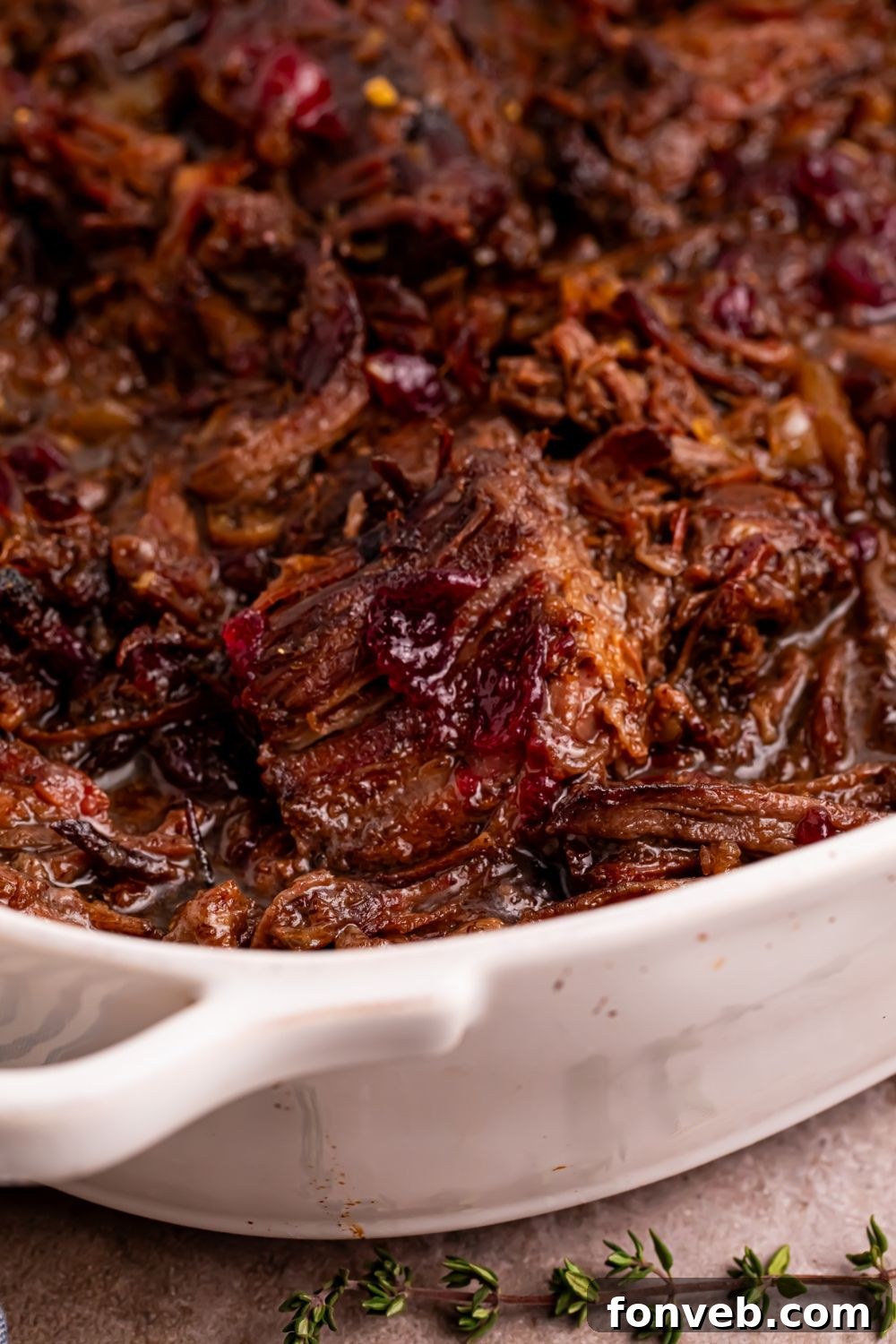 Cranberry Pot Roast shredded and placed  in a casserole pan on table 