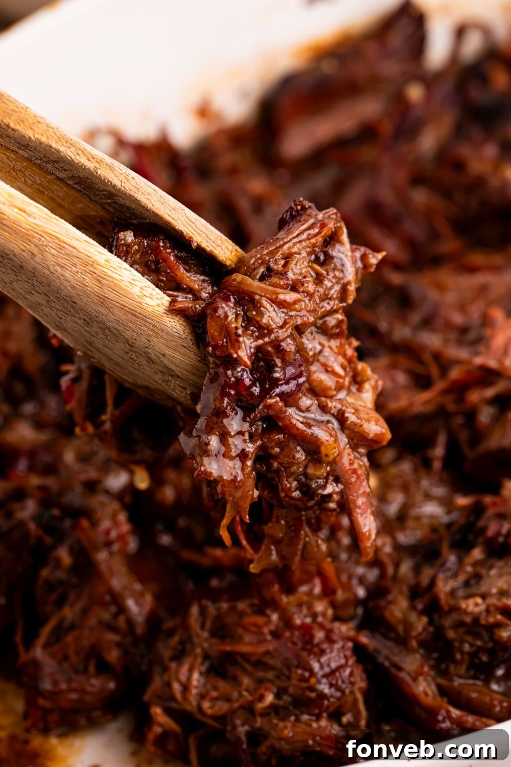 Cranberry Pot Roast shredded with tongs picking up some meat 