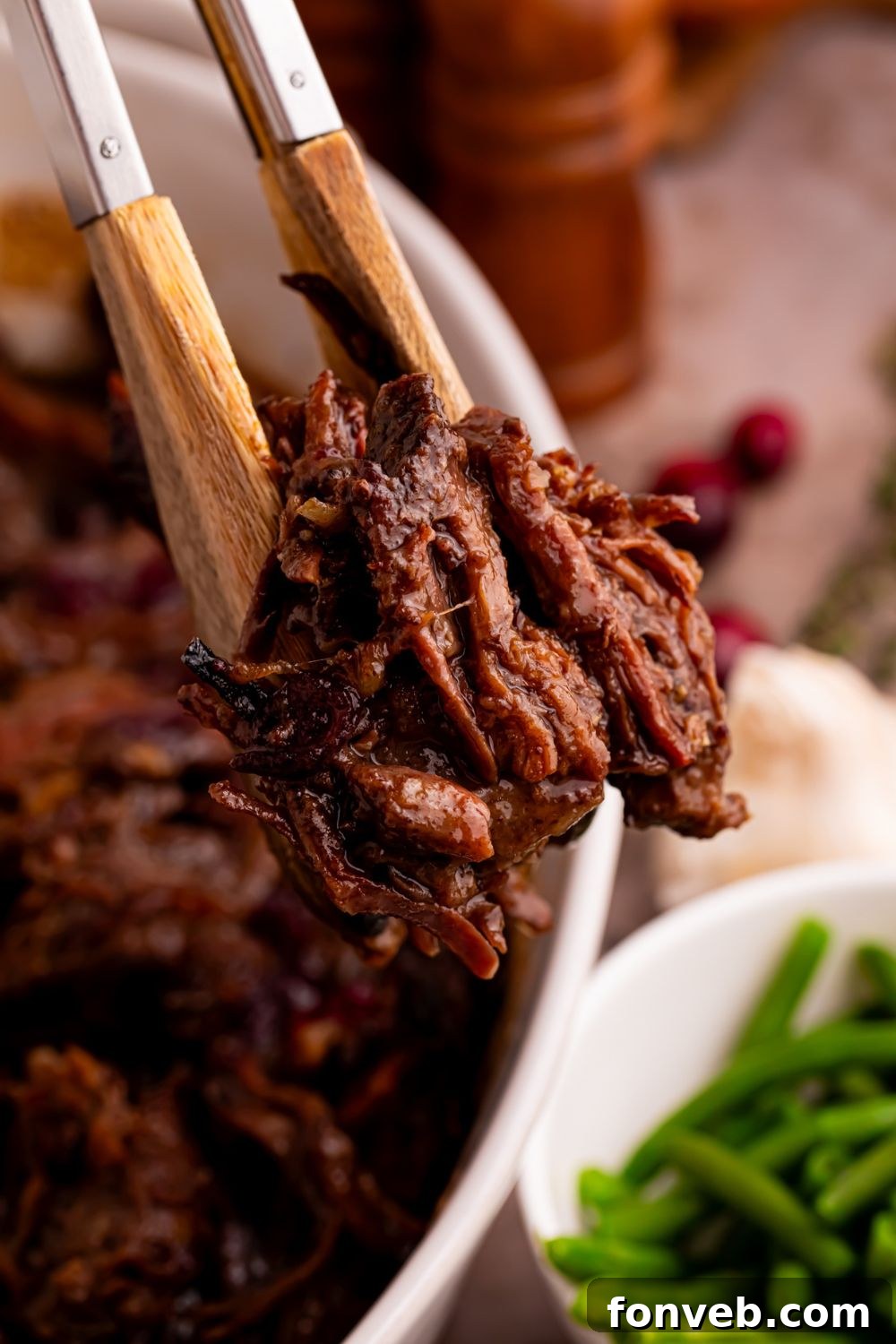tongs with some shredded cranberry roast in it