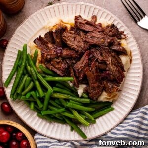 Cranberry Pot Roast on plate with mashed potatoes and fresh green beans and a fork to side on table