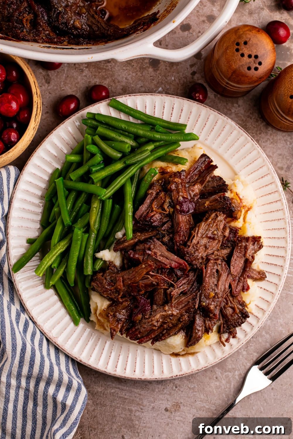 Cranberry Pot Roast on plate with mashed potatoes under it and green beans on side