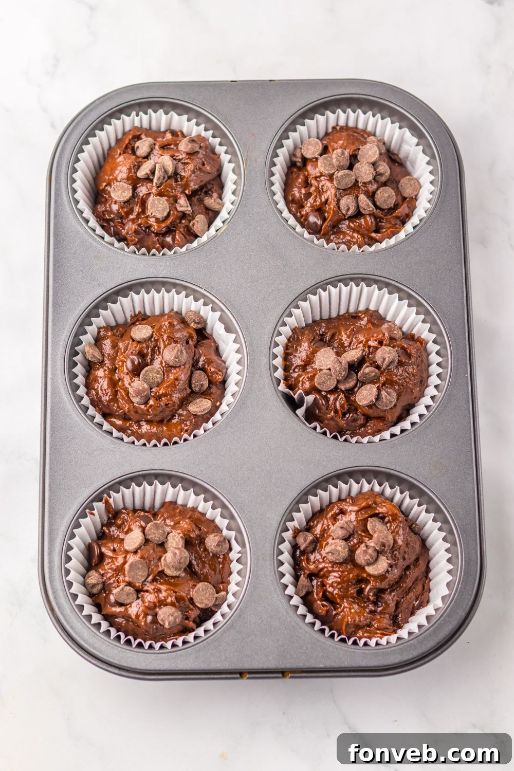 raw Costco Double Chocolate Muffin batter in a muffin pan on table