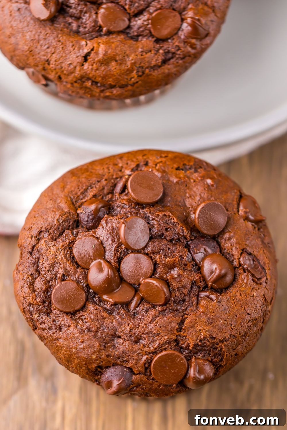 close up look of homemade Costco Double Chocolate Muffins on table with more on a plate behind it