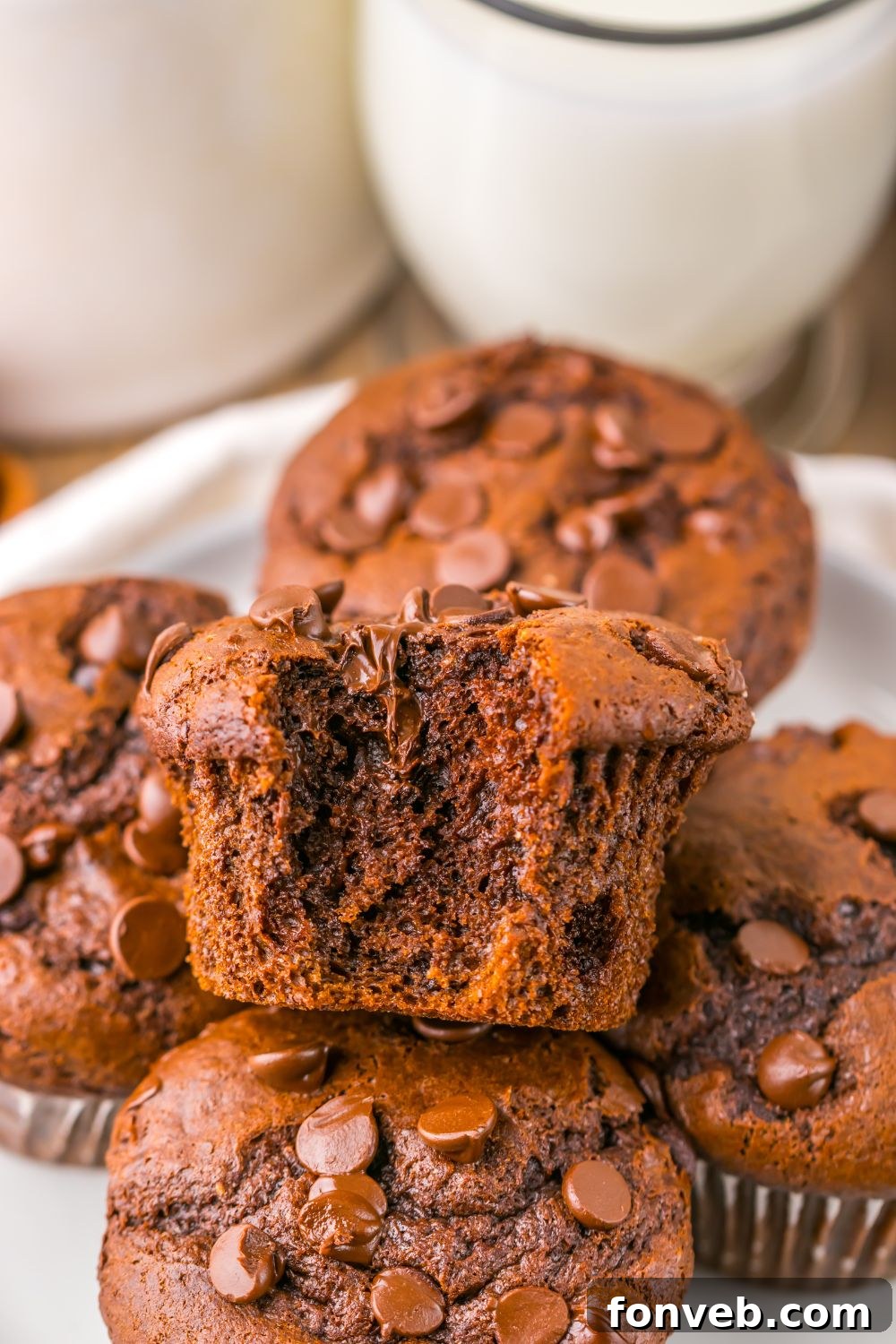 Costco Double Chocolate Muffins stacked on plate with a bite taken out of the top muffin on pile