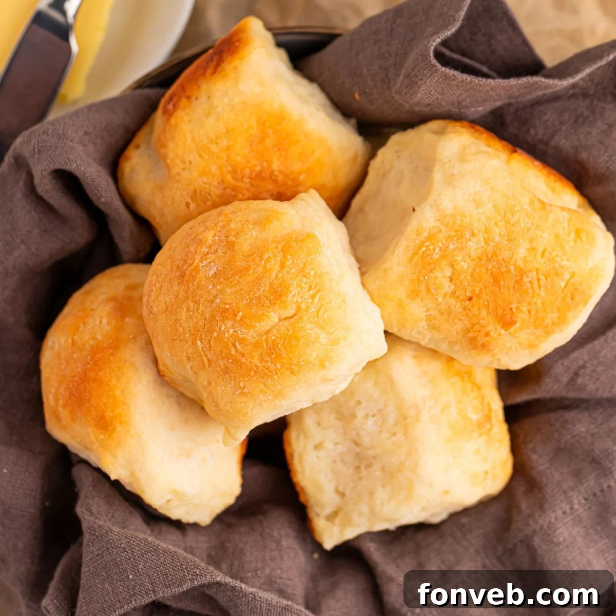 Freshly baked 2-Ingredient Dinner Rolls arranged in a rustic basket lined with a clean towel, highlighting their golden-brown tops and soft appearance, ready to be served.