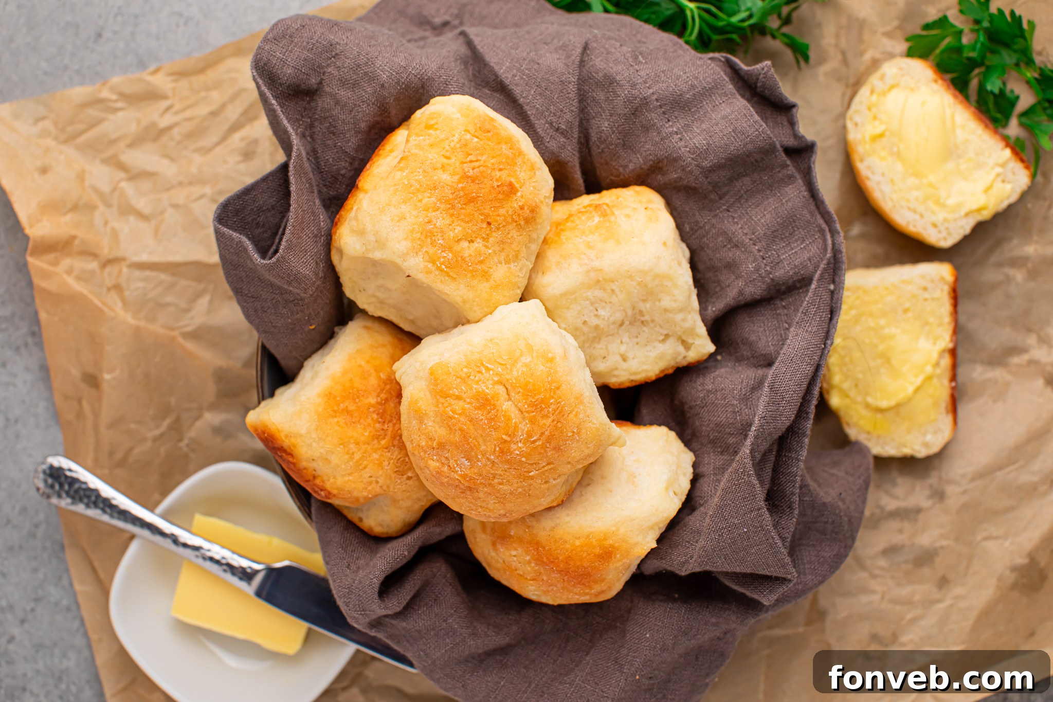 Freshly baked 2-Ingredient Dinner Rolls presented in a charming bread basket, with a small dish of butter on the side, creating an inviting and wholesome scene.