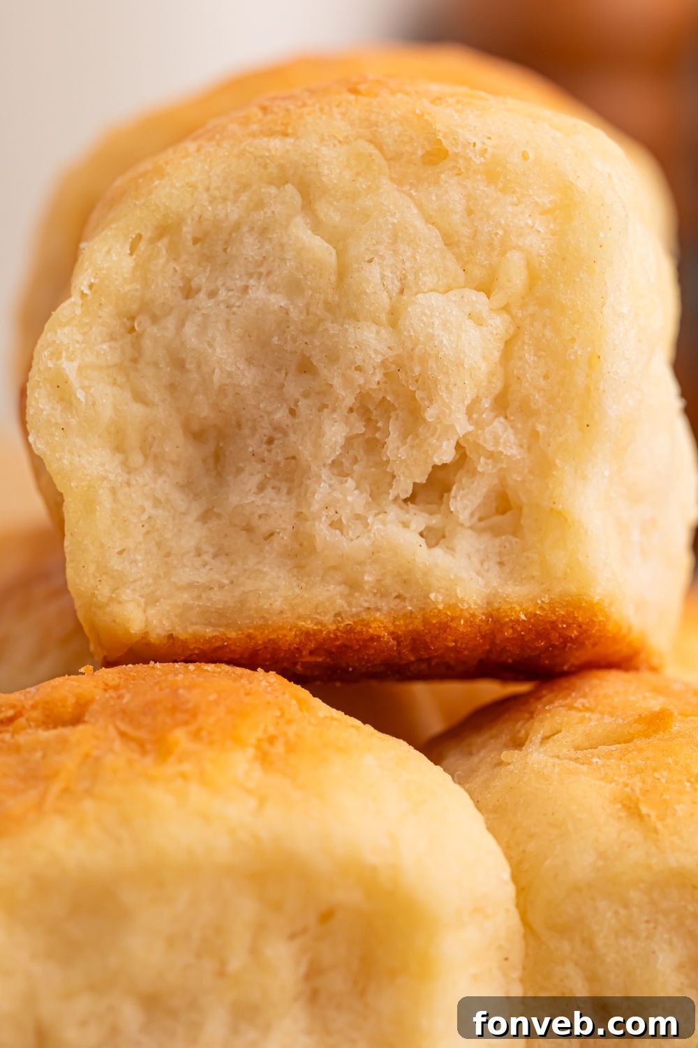 A close-up of two 2-Ingredient Dinner Rolls stacked one on top of the other, showcasing their light and airy texture, indicating how fluffy they are.