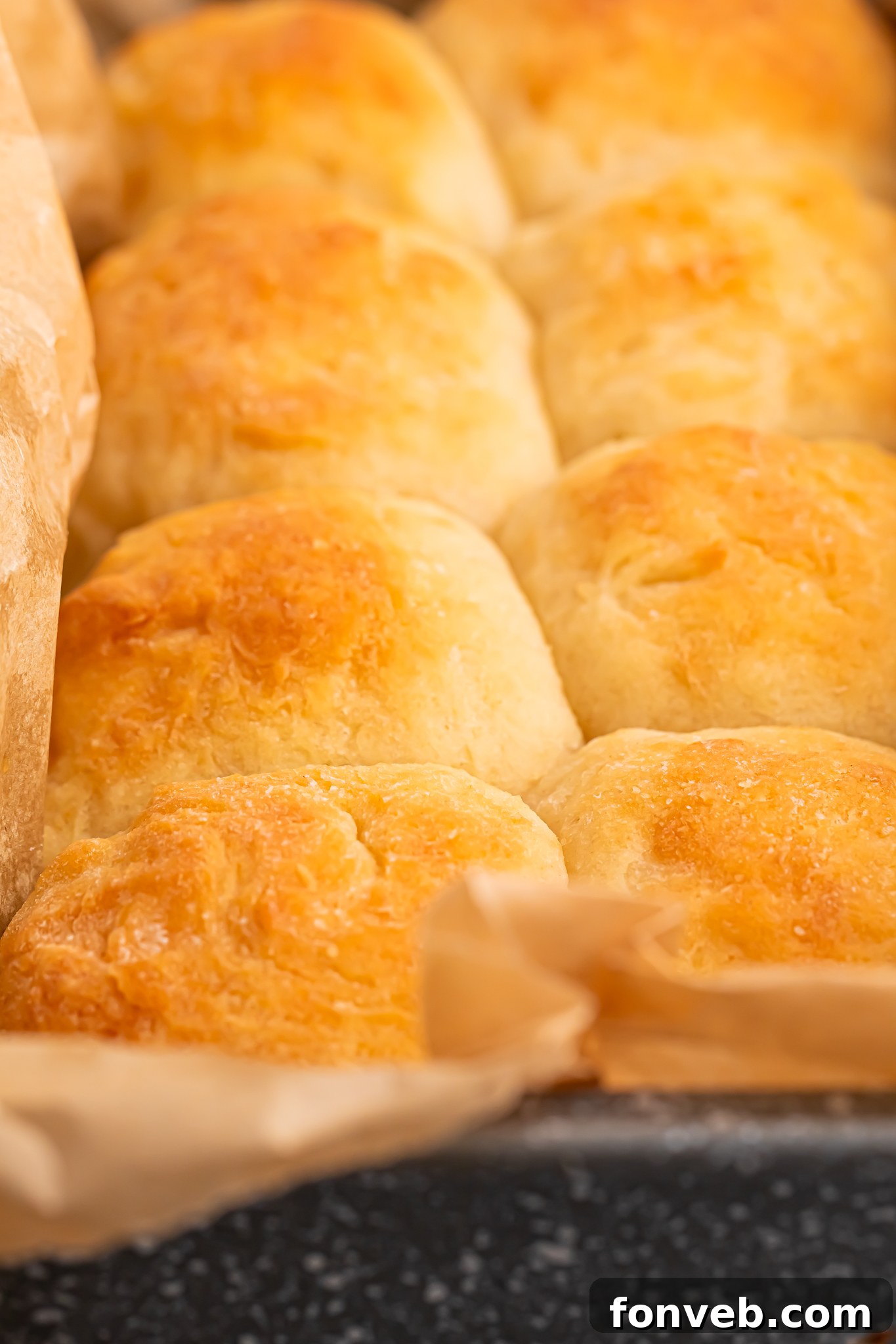 A closer view of the 2-Ingredient Dinner Rolls in a baking pan with parchment paper on a table, showing their perfectly risen and golden surfaces, ready to be enjoyed.