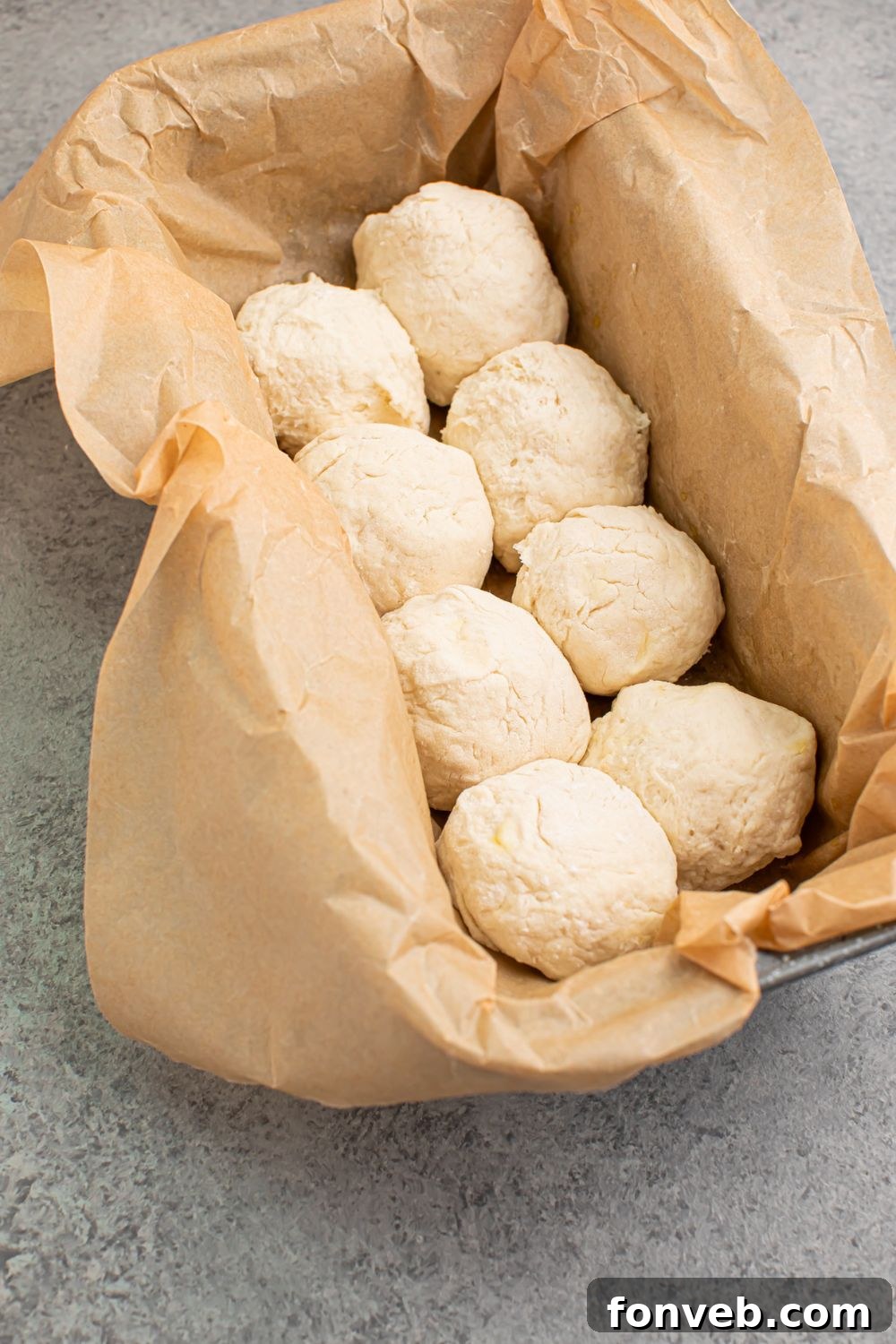 Raw 2-Ingredient Dinner Rolls neatly placed in a baking pan lined with parchment paper, positioned slightly apart to allow for even baking and rising, ready for the oven.