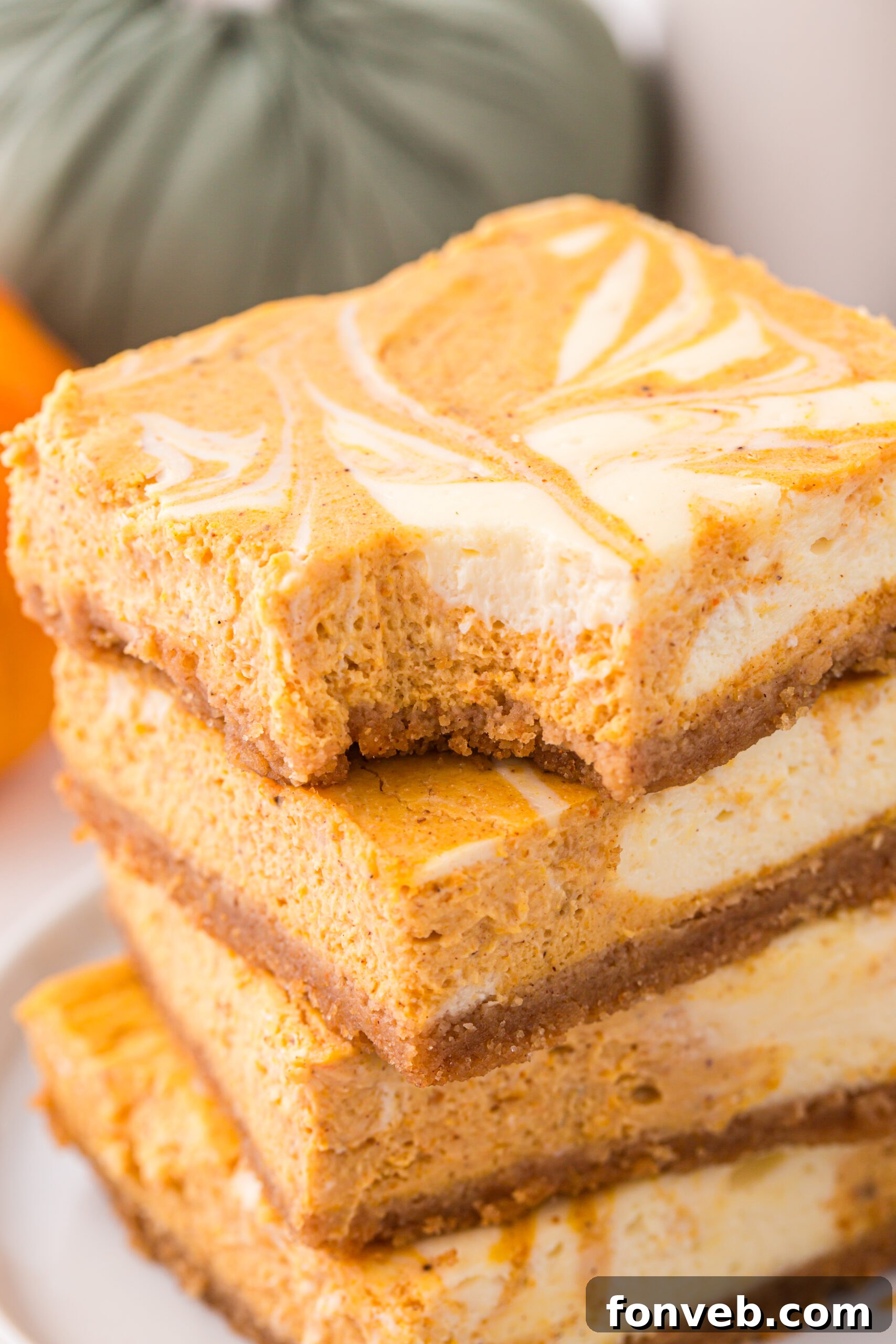 Sliced Swirled Pumpkin Cheesecake Bars stacked with a bite missing from the top one 