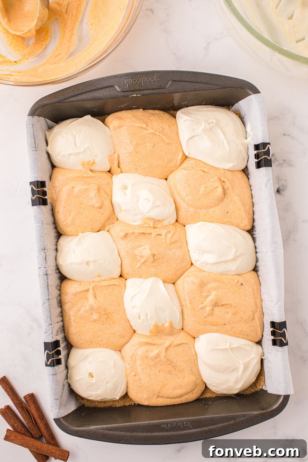 dollops of cheesecake bars on table for Swirled Pumpkin Cheesecake Bars in a pan