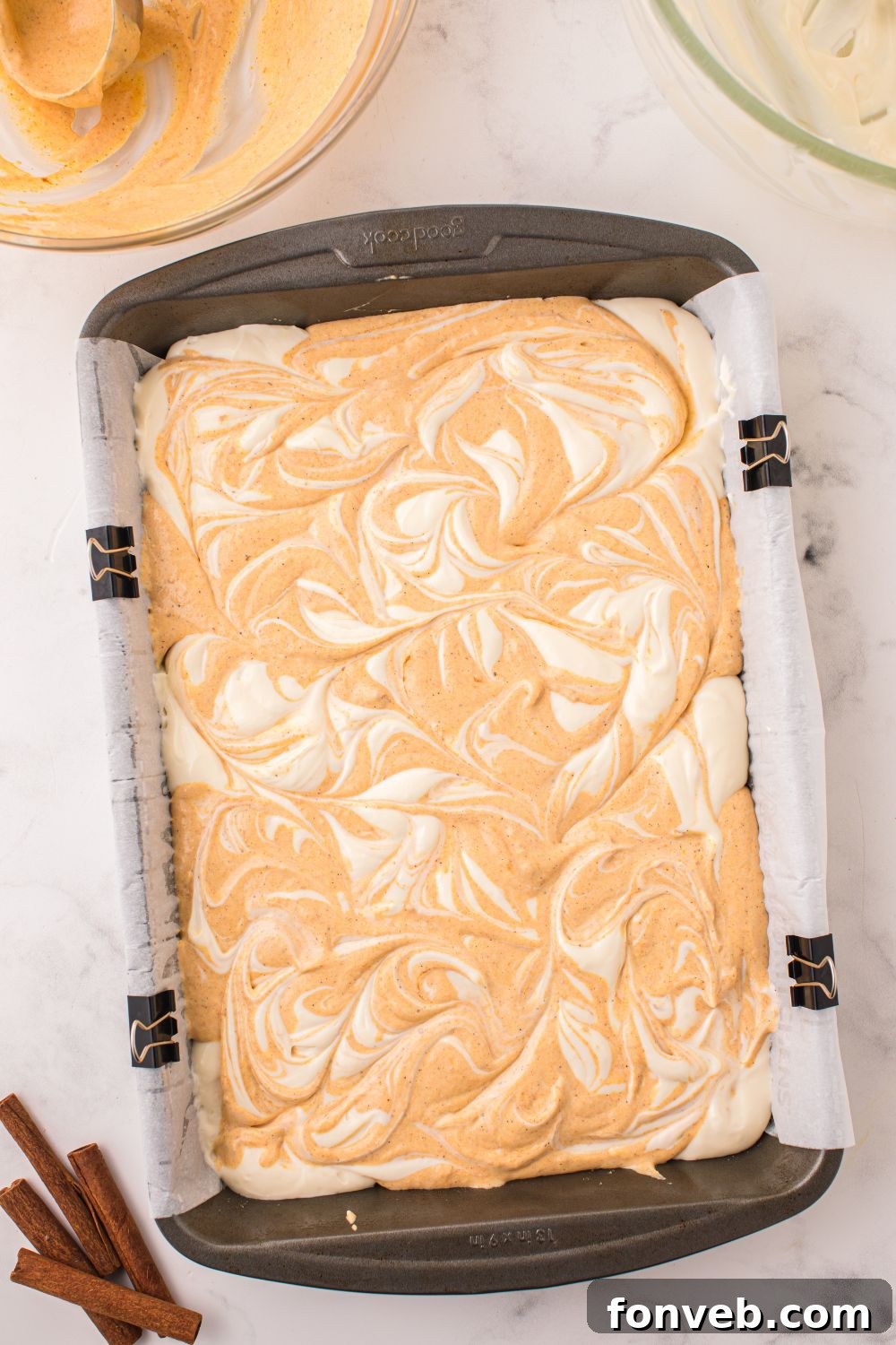 raw batter for Swirled Pumpkin Cheesecake Bars in pan on table