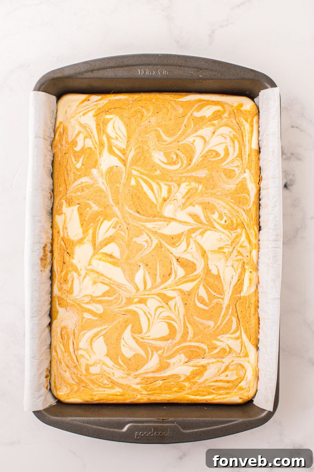 overhead look of baked Swirled Pumpkin Cheesecake Bars in pan on table