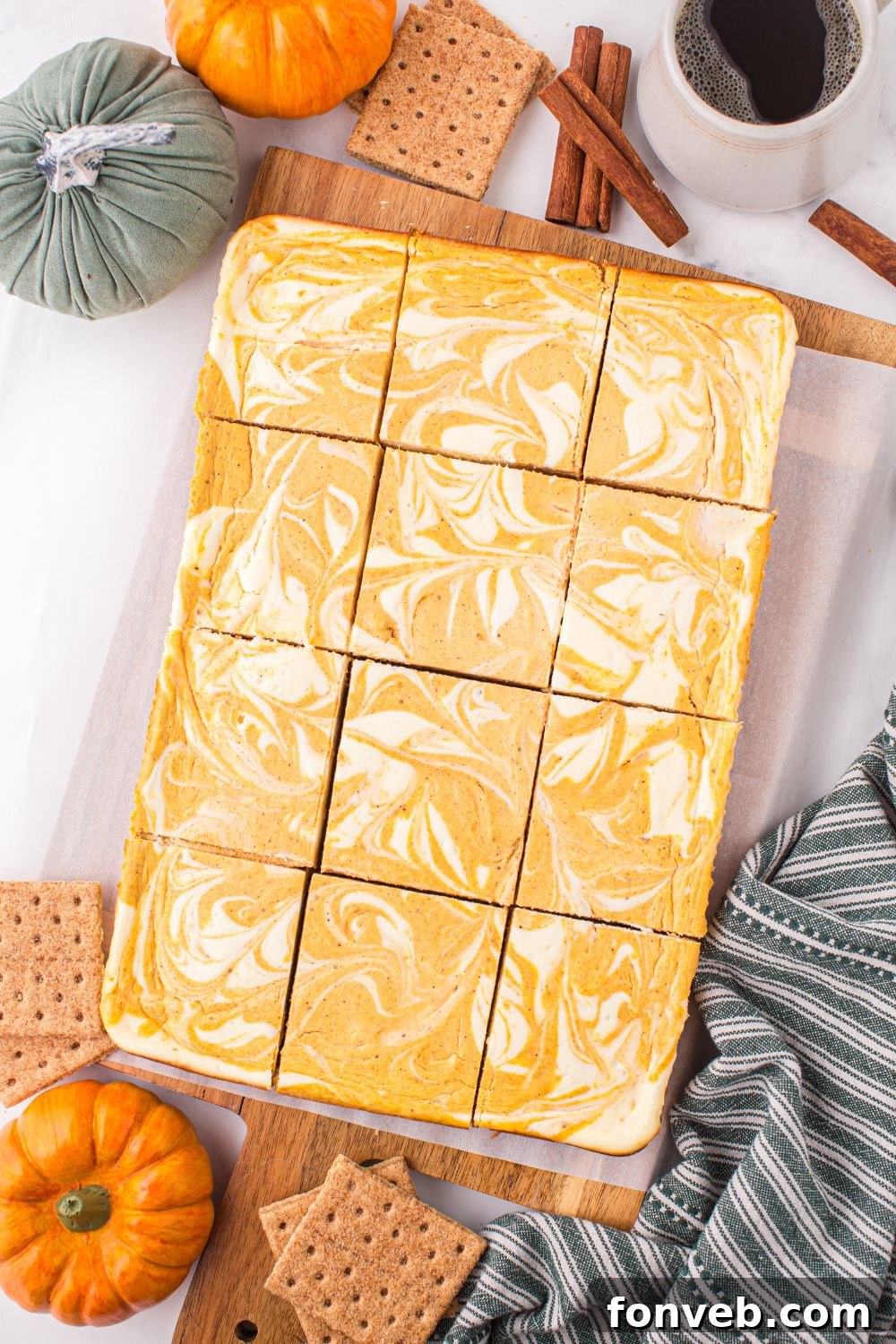 Swirled Pumpkin Cheesecake Bars sliced and placed on table with mini cheesecakes to side