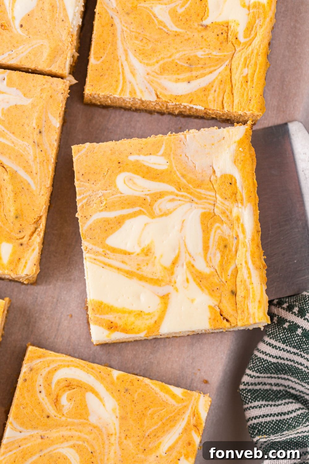 sliced Swirled Pumpkin Cheesecake Bars on table with a spatula under one
