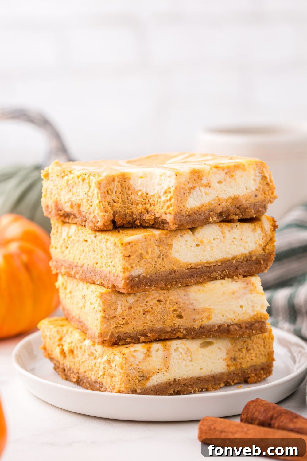 stack of Swirled Pumpkin Cheesecake Bars on plate and a bite taken out of it