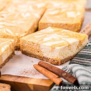 Swirled Pumpkin Cheesecake Bars placed on table with cinnamon sticks in front of bars