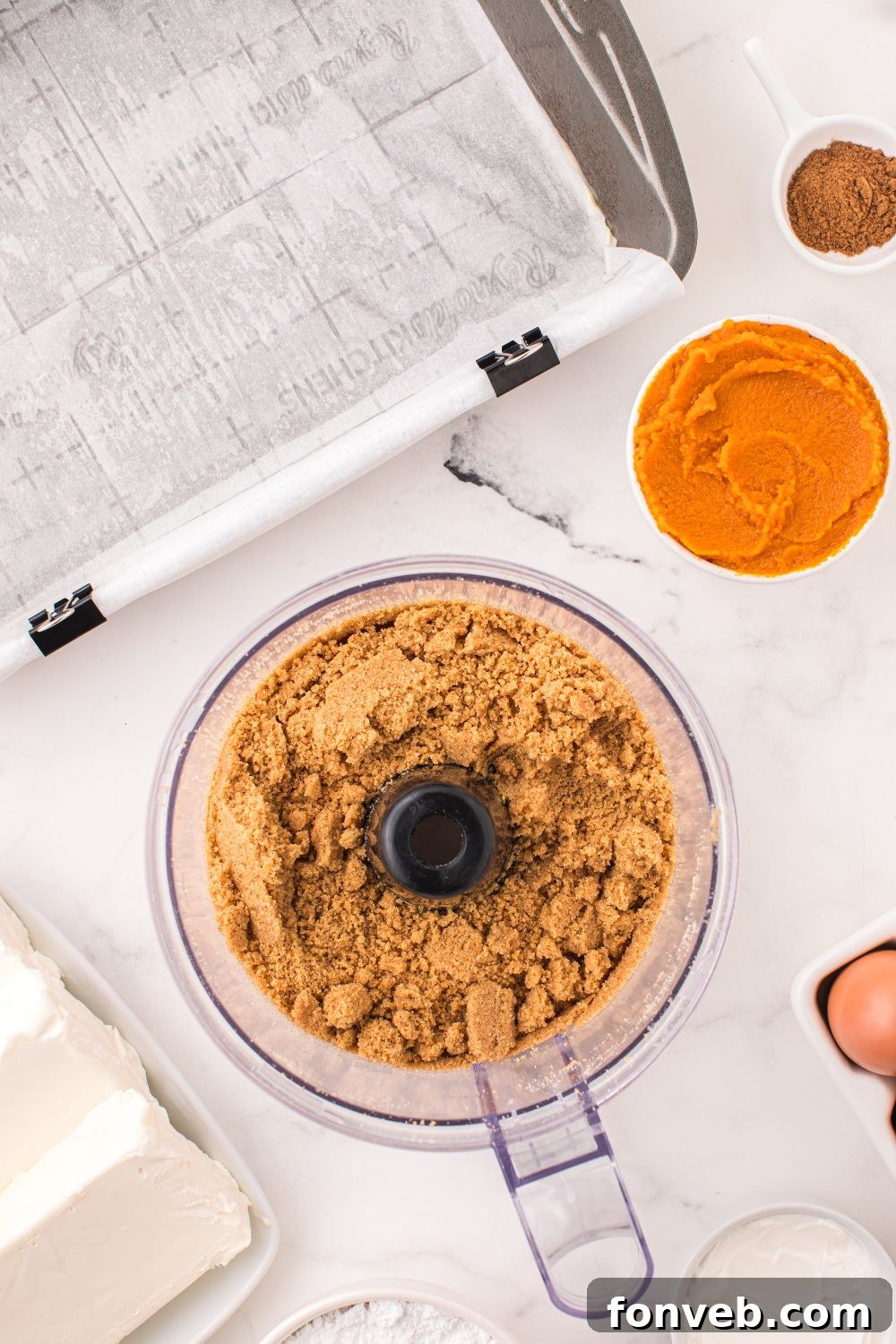graham crackers in a food processor crushed, and pumpkin puree in bowl next to it