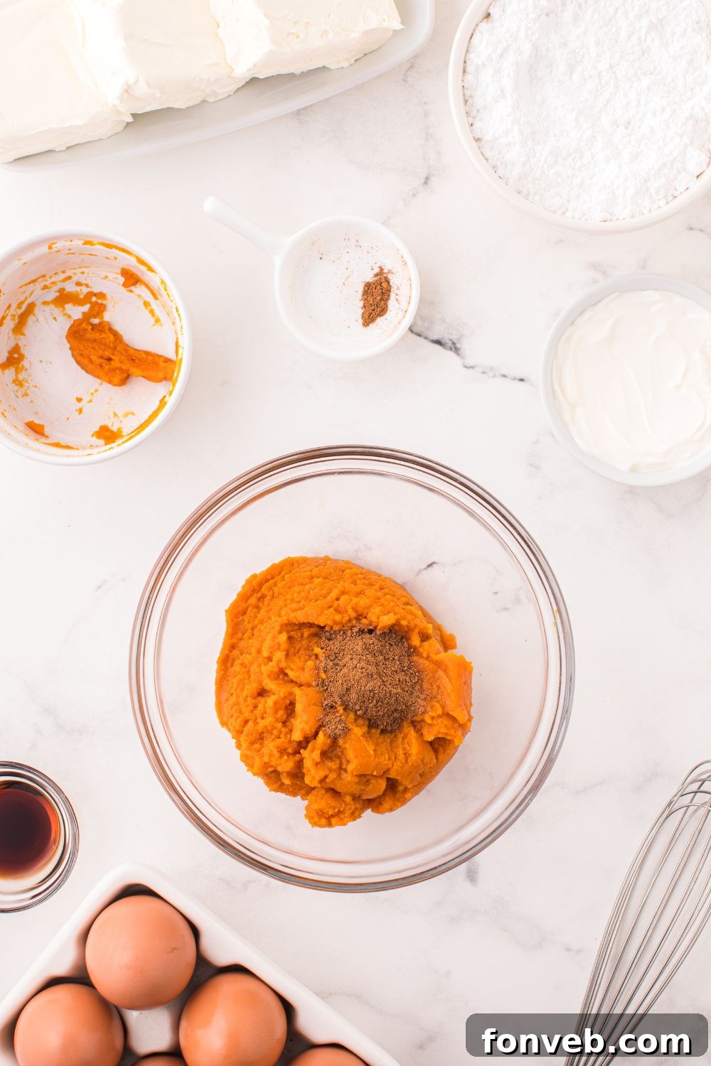 pumpkin puree and spices in a glass bowl on table for making Swirled Pumpkin Cheesecake Bars