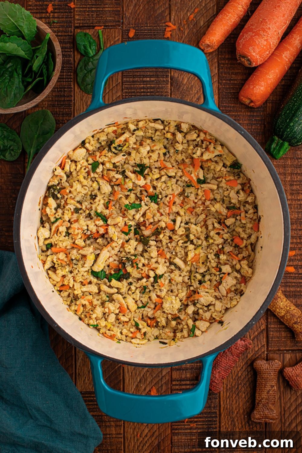 overhead look of Homemade Turkey and Rice Dog Food with Veggies in a blue pot with fresh herbs and whole carrots behind the pot on table 