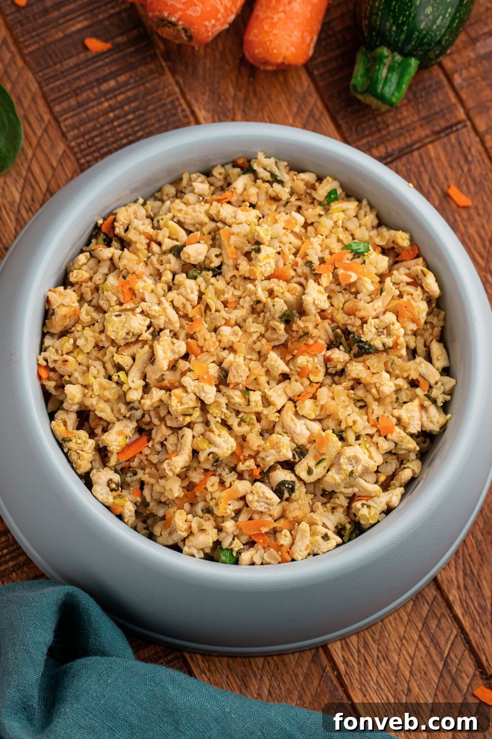 Homemade Turkey and Rice Dog Food with Veggies in a container sitting on table with carrots and zucchini to the side 