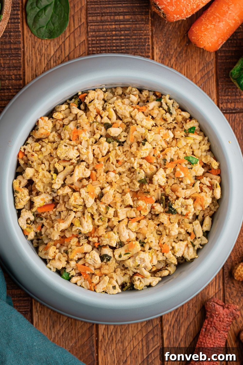 overhead look of Homemade Turkey and Rice Dog Food with Veggies in a dog bowl with a green towel to side of bowl 