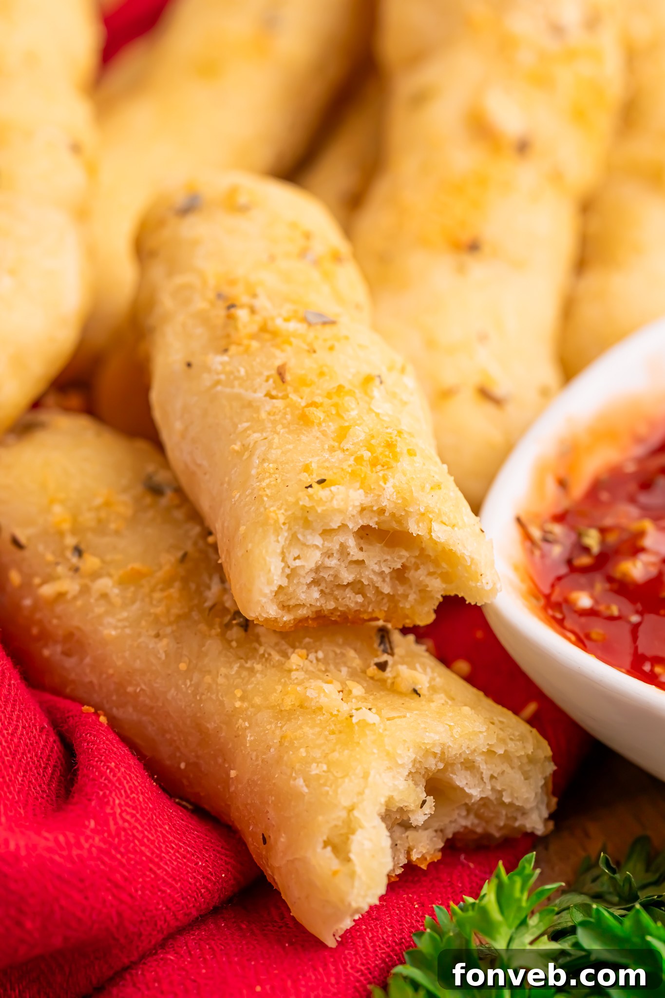 2-Ingredient Buttery Garlic Parmesan Breadsticks 2 2 Ingredient Garlic Parmesan Breadsticks on table with one torn in half and a small bowl of marinara sauce