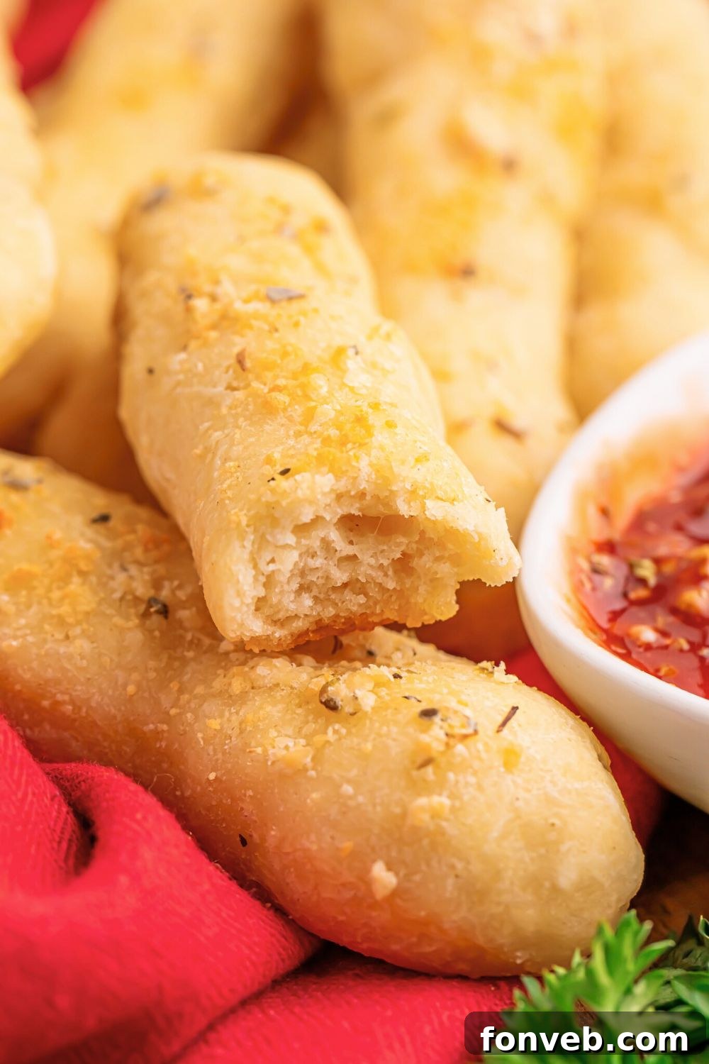 2-Ingredient Buttery Garlic Parmesan Breadsticks 19 2 Ingredient Garlic Parmesan Breadsticks with a bite taken out of it with sauce to side