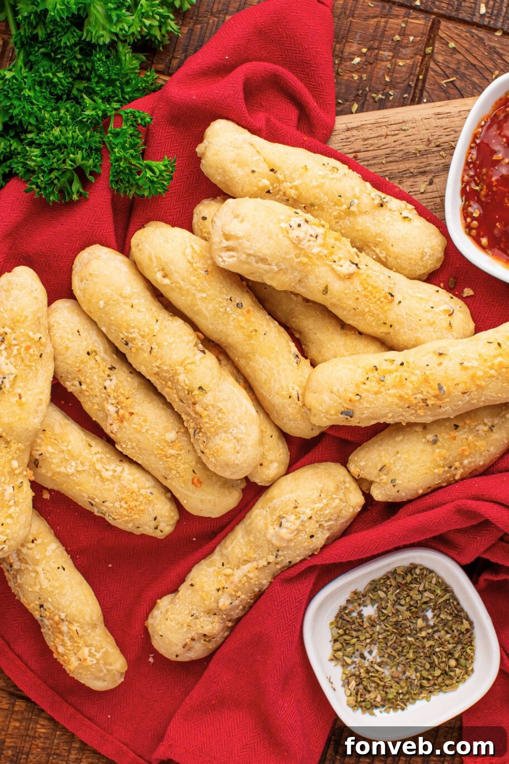 2-Ingredient Buttery Garlic Parmesan Breadsticks 20 2 Ingredient Garlic Parmesan Breadsticks on table with a red towel under and parsley to side