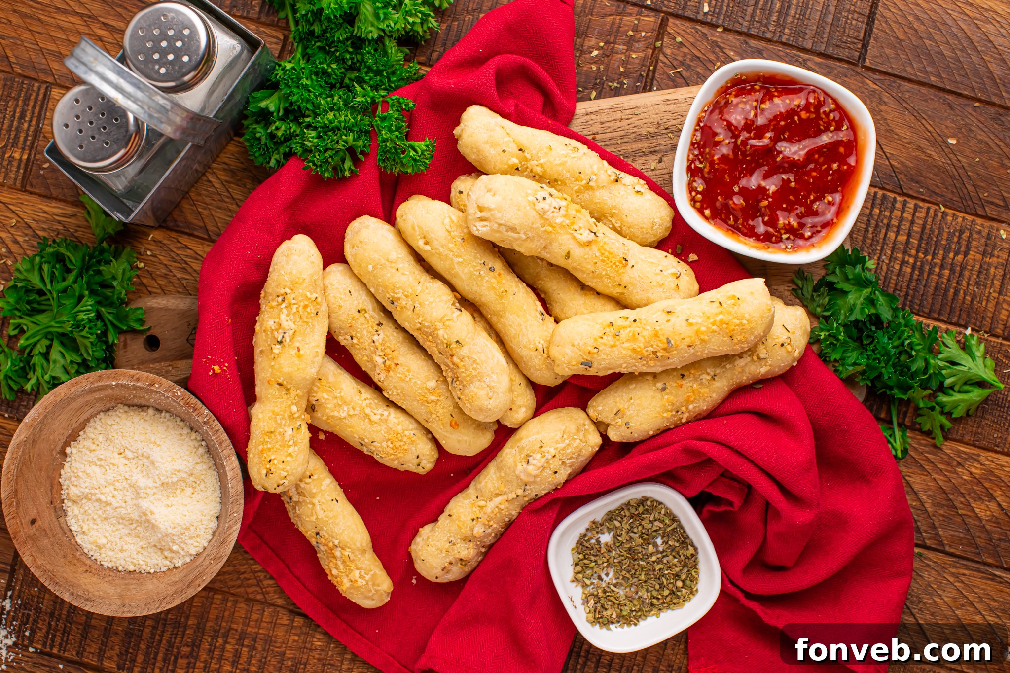 2-Ingredient Buttery Garlic Parmesan Breadsticks 25 overhead look of breadsticks with small bowls of sauce, parmesan cheese & oregano