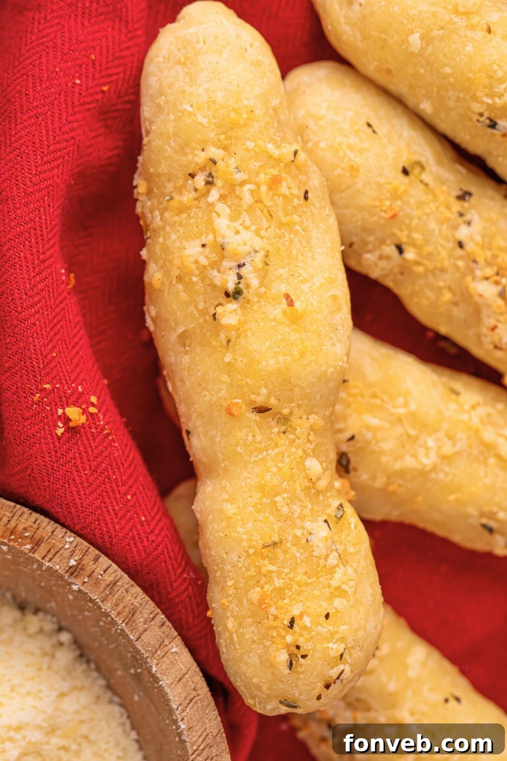 2-Ingredient Buttery Garlic Parmesan Breadsticks 5 2 ingredient breadsticks in a basket with a red towel and some parmesan cheese to the side