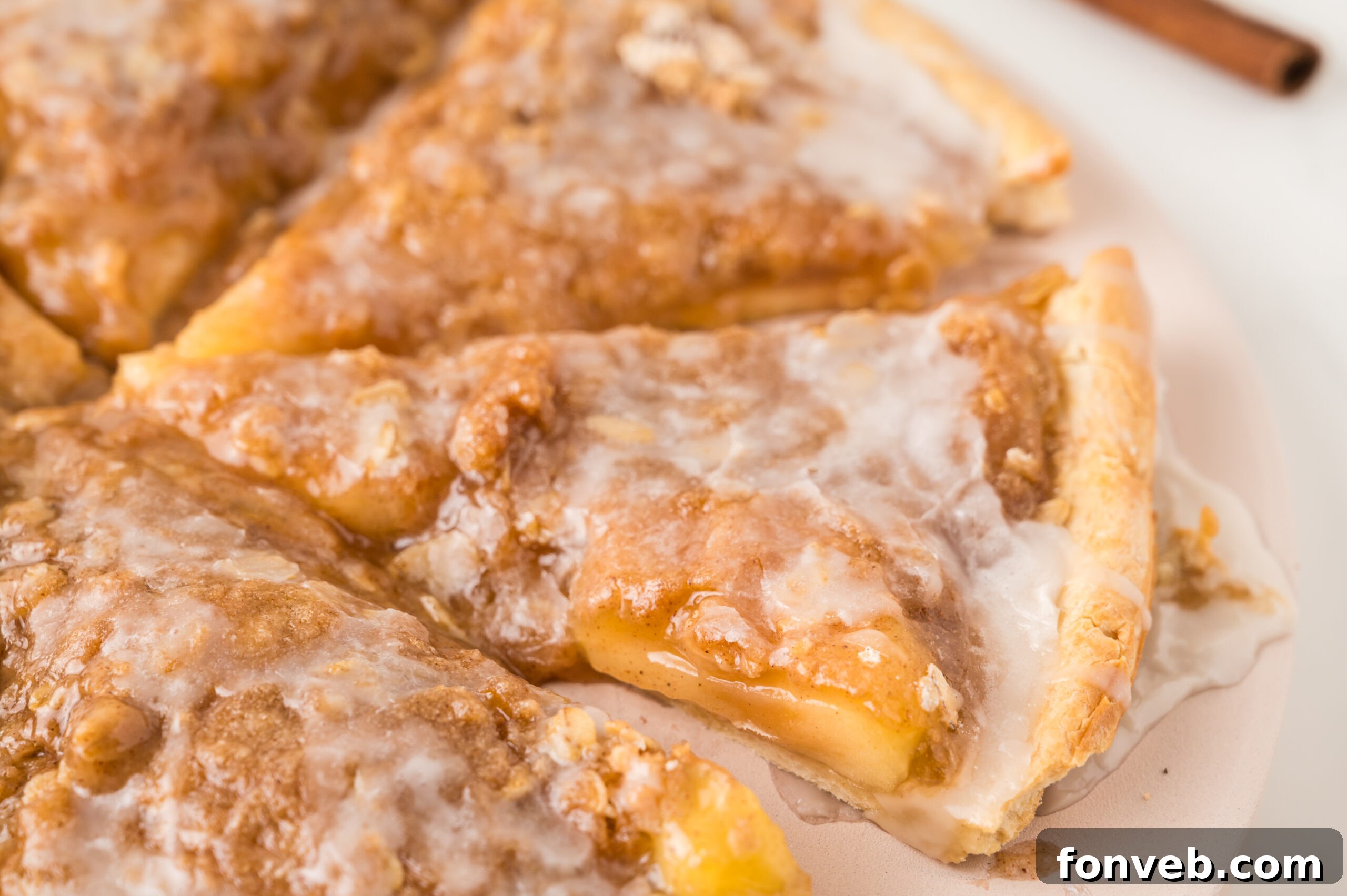 A close-up of a rustic Apple Pie Pizza, showing the textural contrast of the crisp crumble and soft apple filling, sitting on a wooden surface.