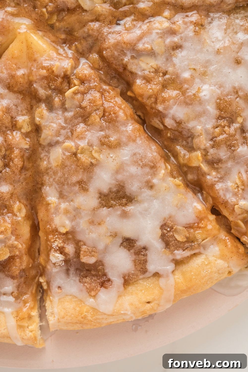 A close-up view of three slices of Apple Pie Pizza, showing the delicious layers of apple filling, crumble, and vanilla icing, ready to be enjoyed.