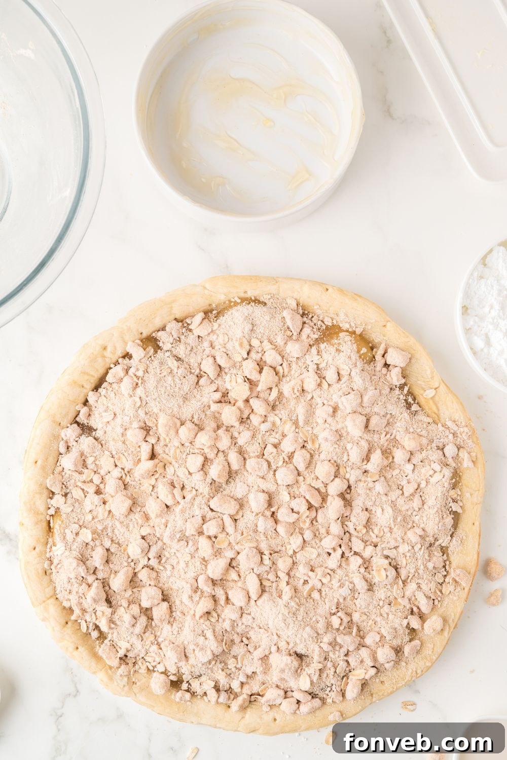 An irresistible oat crumble topping evenly distributed over the sweet apple pie filling, promising a delightful crunch.