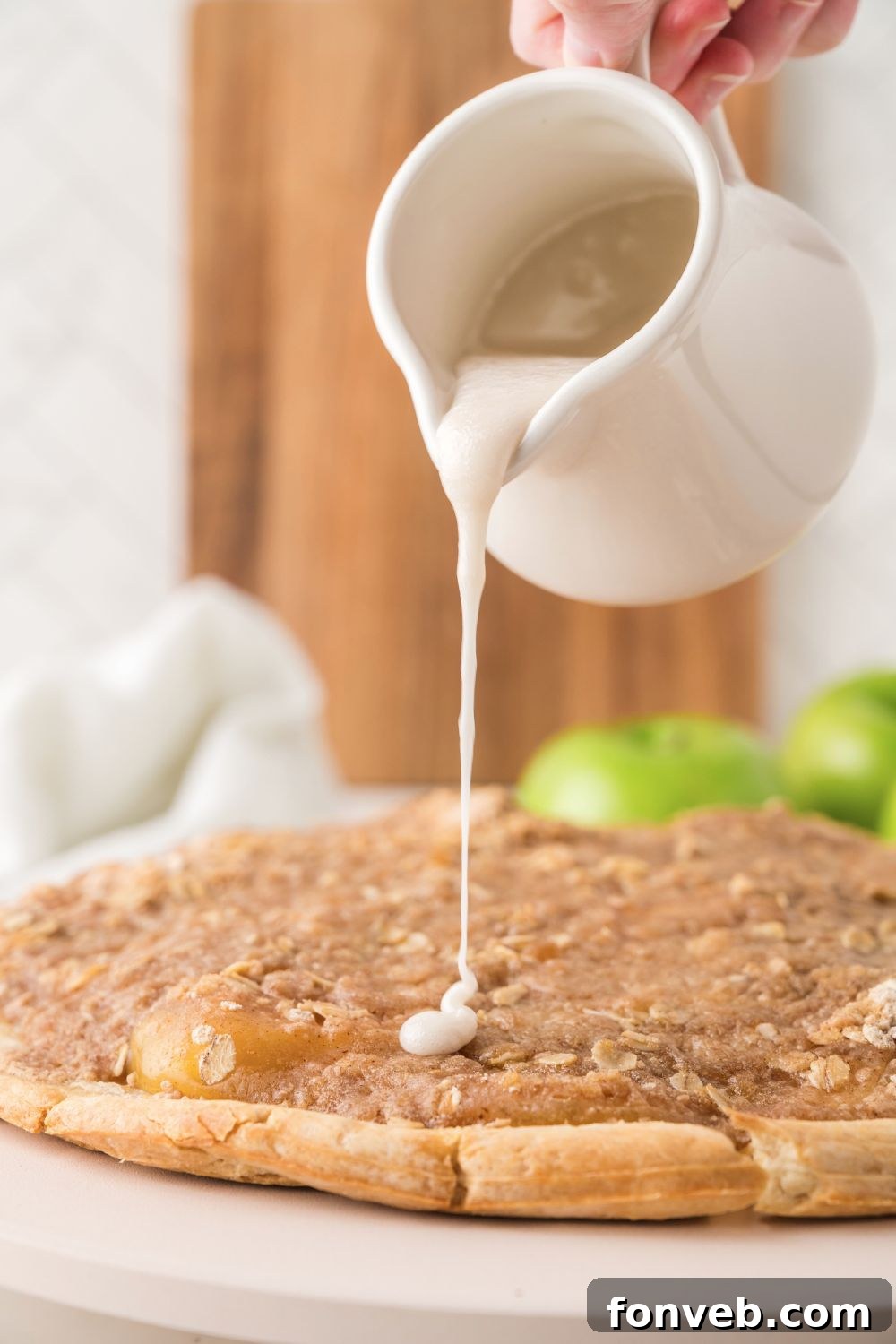 The finished Apple Pie Pizza, artfully drizzled with a sweet vanilla glaze, ready to be sliced and served.