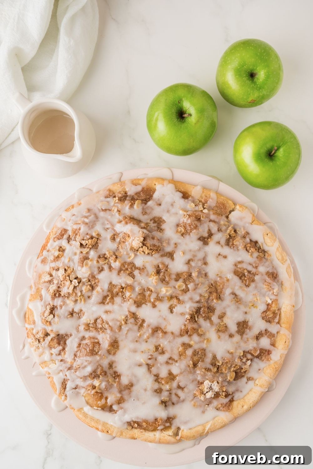A whole Easy Apple Pie Pizza on a wooden table, with fresh green apples placed alongside it, emphasizing its natural, wholesome ingredients.