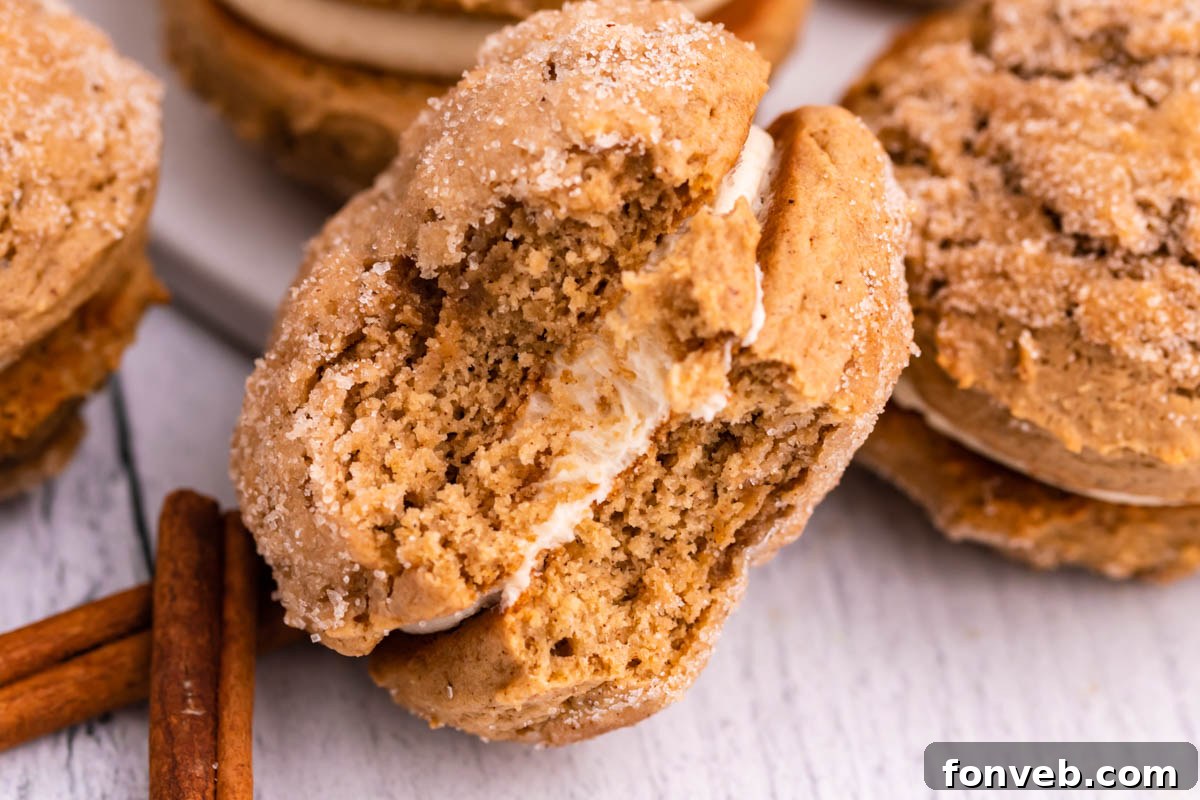 Pillowy Soft Spiced Apple Cider Whoopie Pies 11 Apple Cider Whoopie Pie with a bite missing showing the inside filling